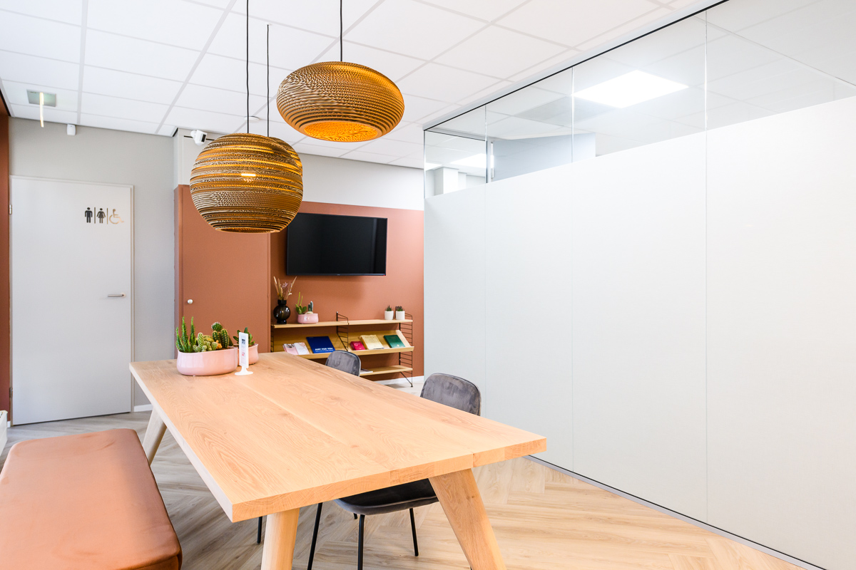 moderne wachtkamer met glazen wand ingericht met eiken tafel en maatwerk bank